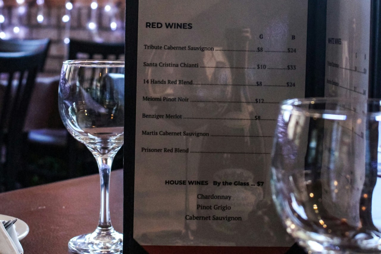 A restaurant wine list showing rows of red wines and prices.
