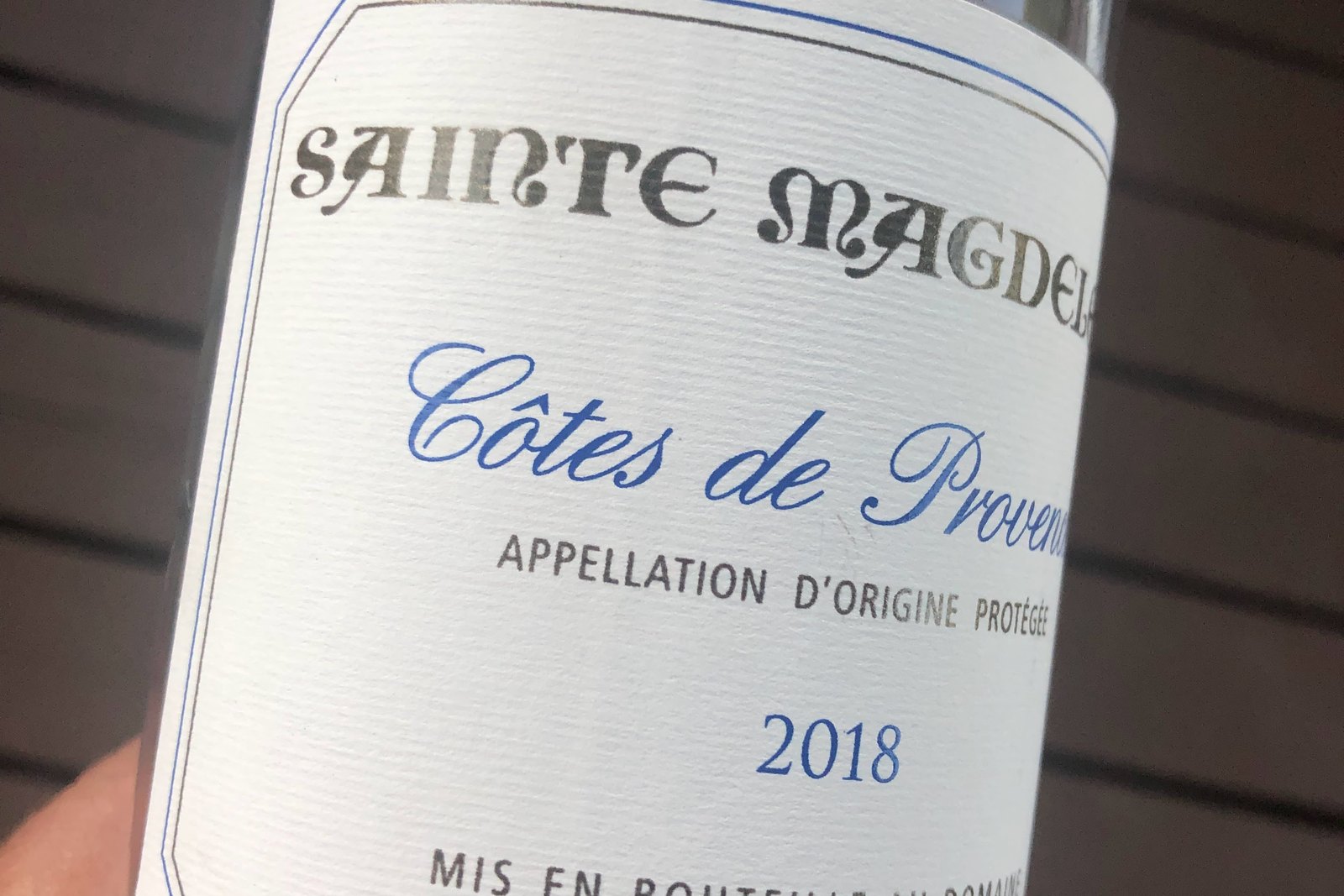Close view of the front label on a bottle of 2018 Sainte Magdeleine Côtes de Provence, held in a hand.